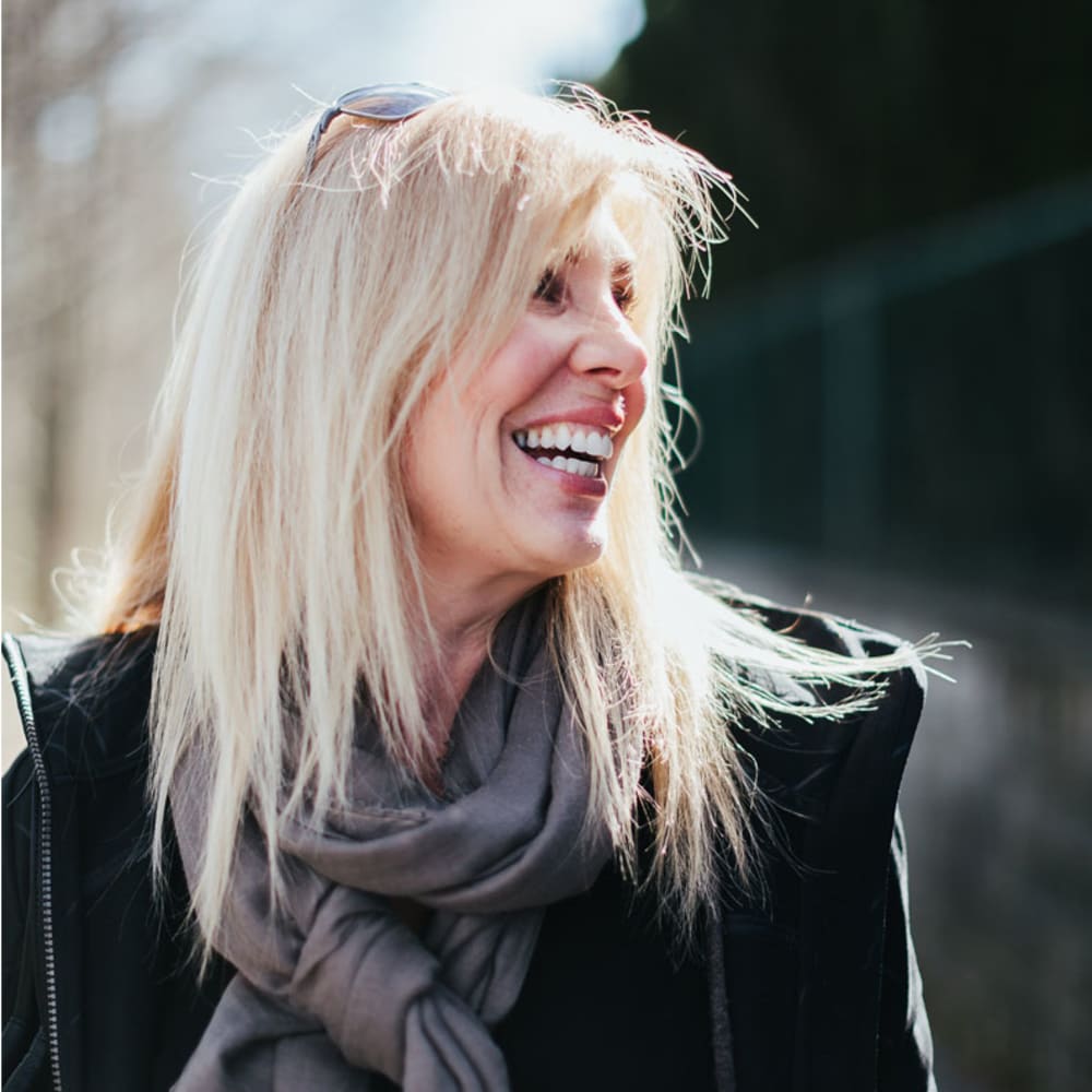 An adult woman with blonde hair smiles and looks to the right.
