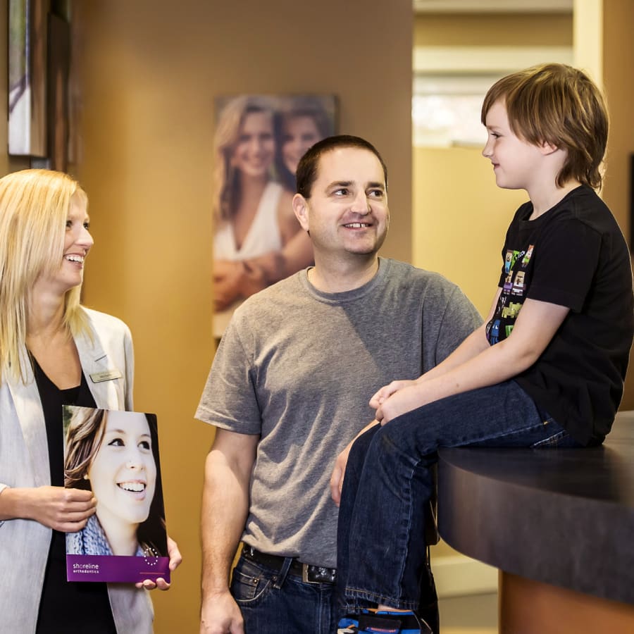 A father and son are greeted by a team member at the Shoreline Orthodontics Campbell River office reception area.
